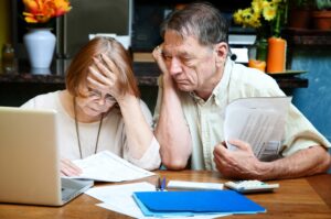 seniors in debt, a senior couple reviewing their financial documents and looking stressed out